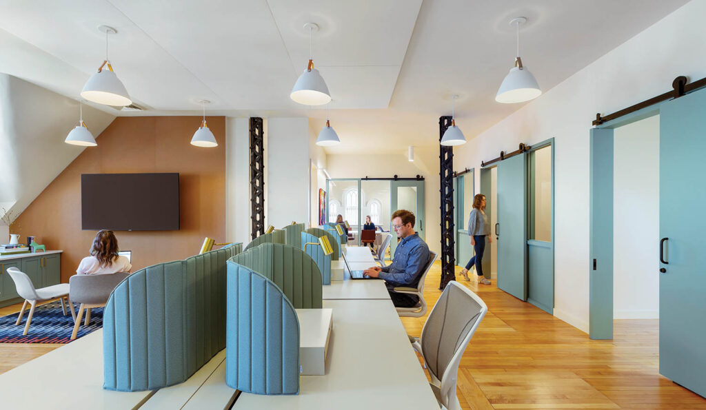 People working in office of museum with adjoining desks and barn doors leading to offices