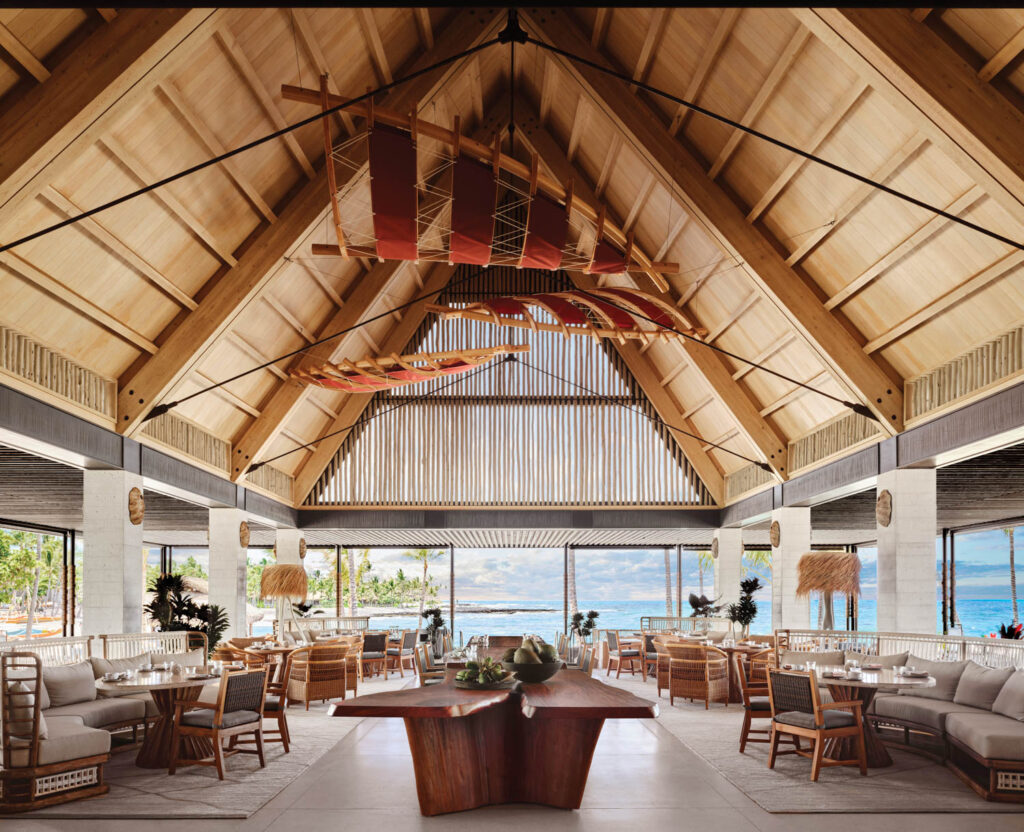 an installation of canoe sails hangs over a mahogany table in this hotel restaurant 