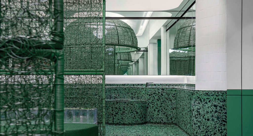 green themed public restroom with bright mirrors and lights