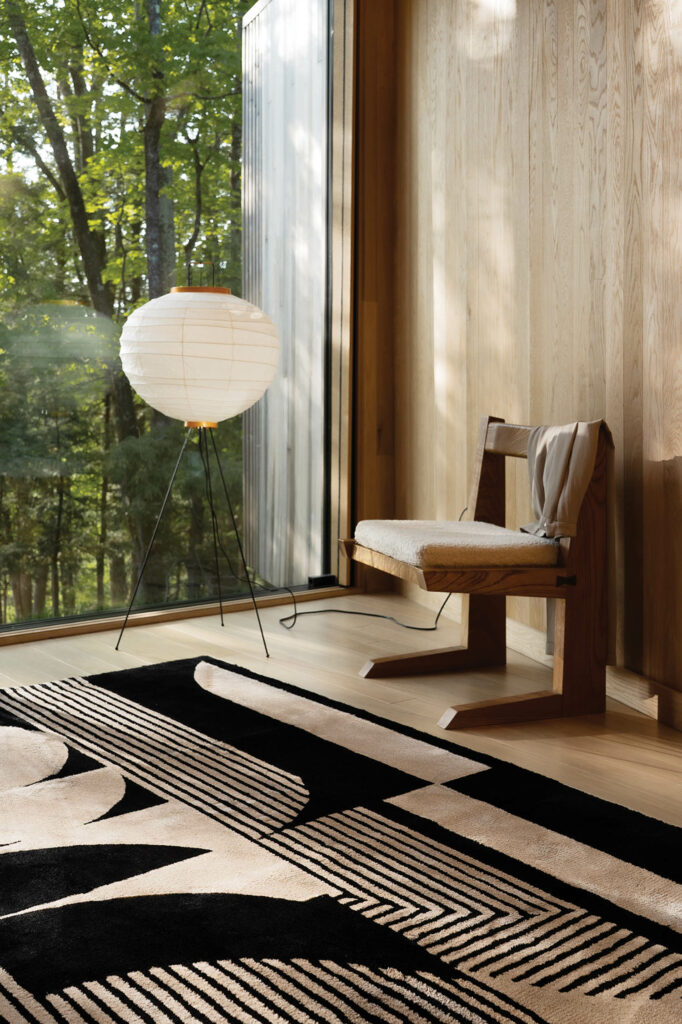 a black and beige abstract rug next to a chair