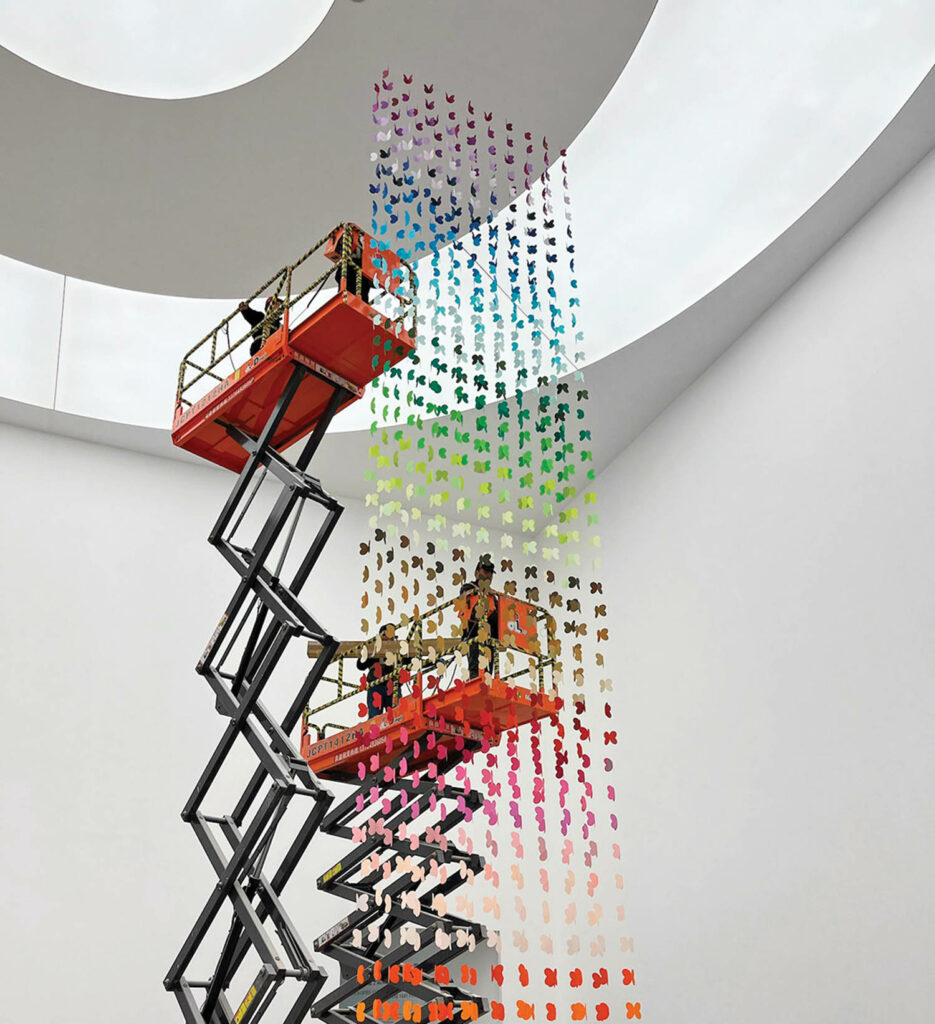 people hanging the rainbow butterflies from the ceiling using scissor lifts.