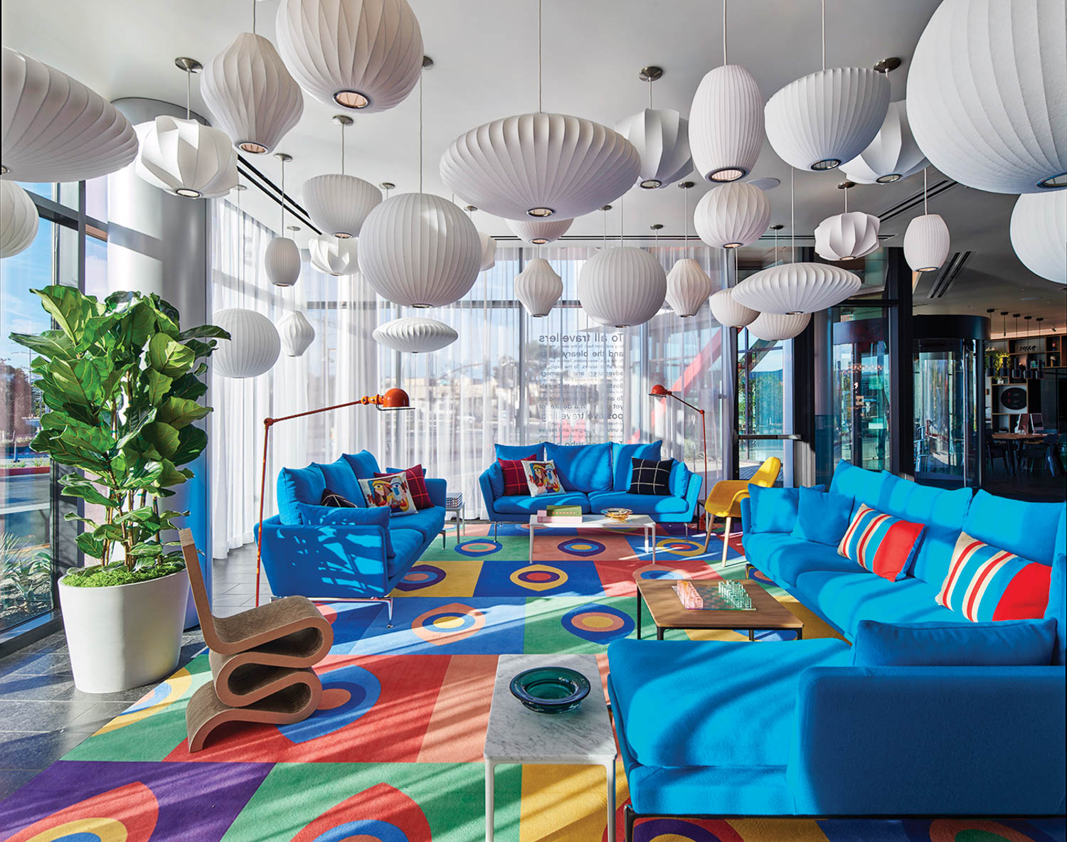 sitting room with colorful carpet, bright blue couches and white lamps